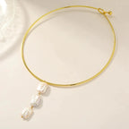 Aura 18K gold plated tubular collar necklace with a vertical drop of three large organic freshwater pearls on a light beige background