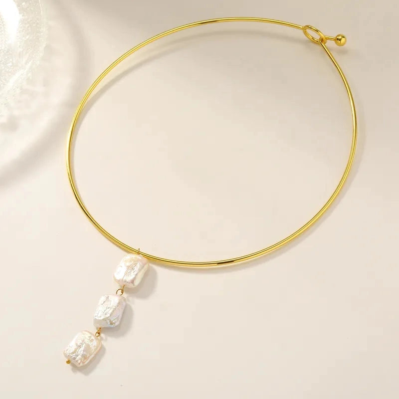 Aura 18K gold plated tubular collar necklace with a vertical drop of three large organic freshwater pearls on a light beige background