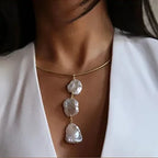 Model wearing a structured Aura 18K gold plated tubular collar necklace with a vertical drop of three large organic freshwater pearls.