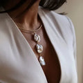 Model wearing a structured Aura 18K gold plated tubular collar necklace with a vertical drop of three large organic freshwater pearls.