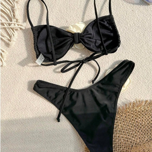 Flora Black Rose Two Piece Bikini with 3D ivory floral accents from 7th of April boutique with a bow detail on a textured surface | 7th of April