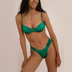 Woman wearing a Laguna Minimalist Two Piece Bikini Set in a high-cut silhouette from 7th of April boutique against a beige background