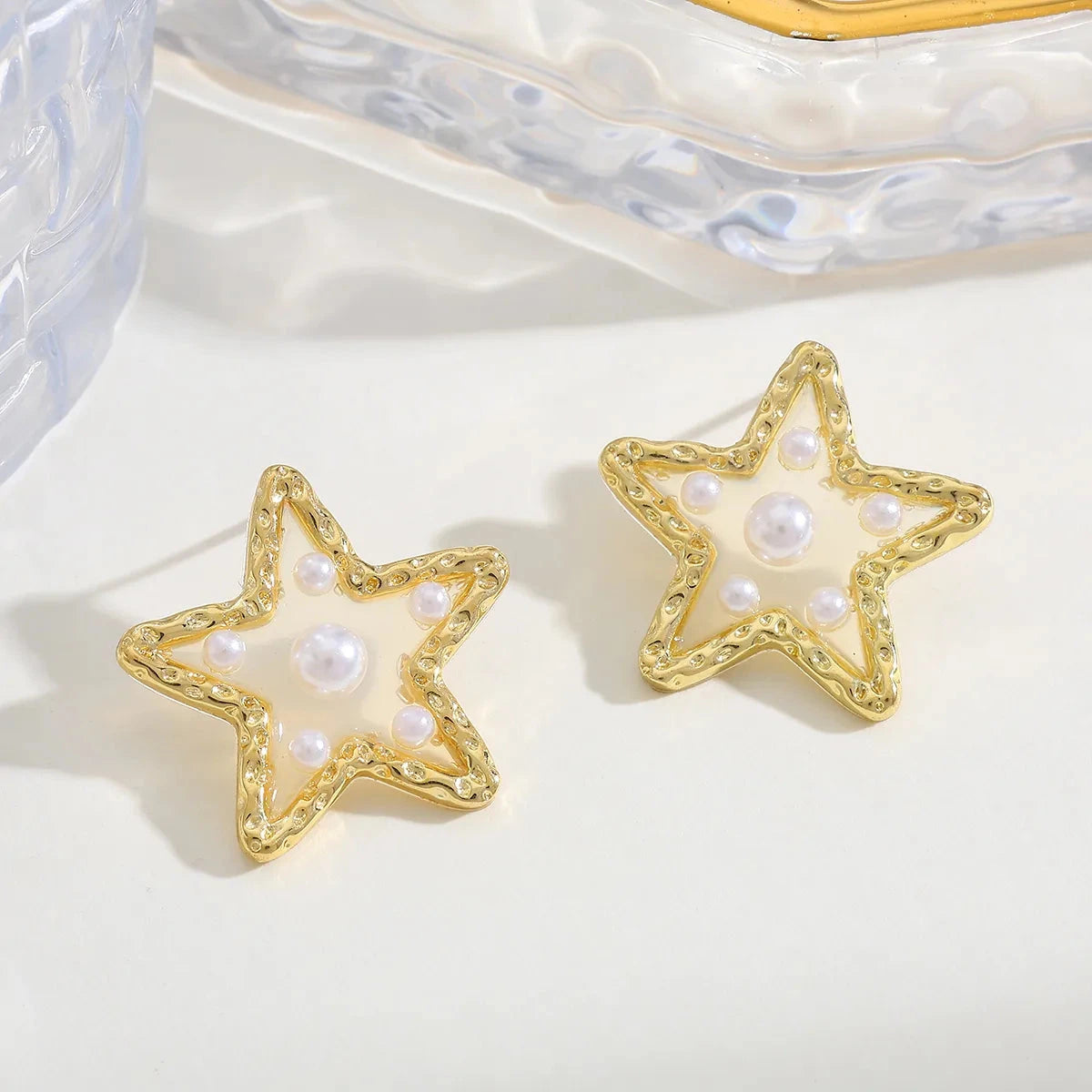 Waterproof Gold Perla Estrella Star Earrings in 18K gold plated stainless steel on a light background
