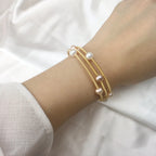 Waterproof Gold Perla Shell Charm Bracelet in 18K gold plated stainless steel on a wrist against a white background