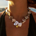 Waterproof Gold Shell Charm Pendant Necklace in 18K gold plated stainless steel worn by a person outdoors. | 7th of April