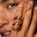 Close-up of a woman's hand with Waterproof Gold Tide Wave Stackable Ring in 18K gold plated stainless steel on her finger, touching her face. |7th of April