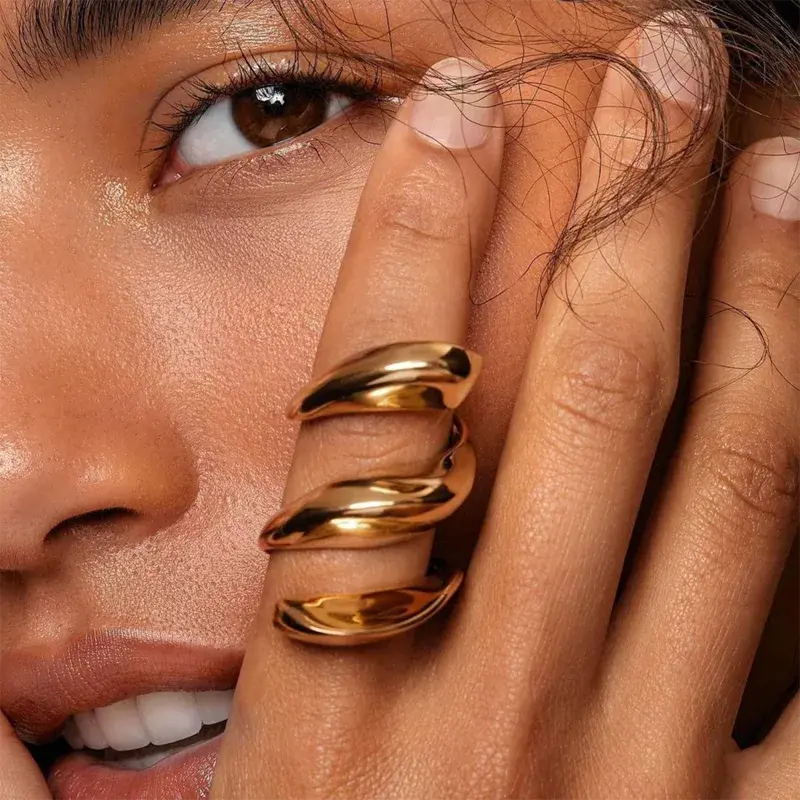 Close-up of a woman's hand with Waterproof Gold Tide Wave Stackable Ring in 18K gold plated stainless steel on her finger, touching her face. |7th of April
